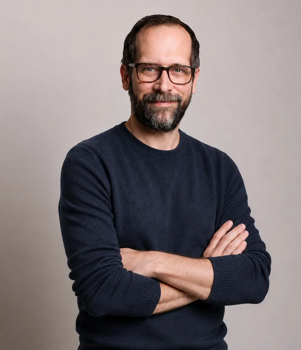 Simon Grundmann mit verschränkten Armen vor hellem Hintergrund